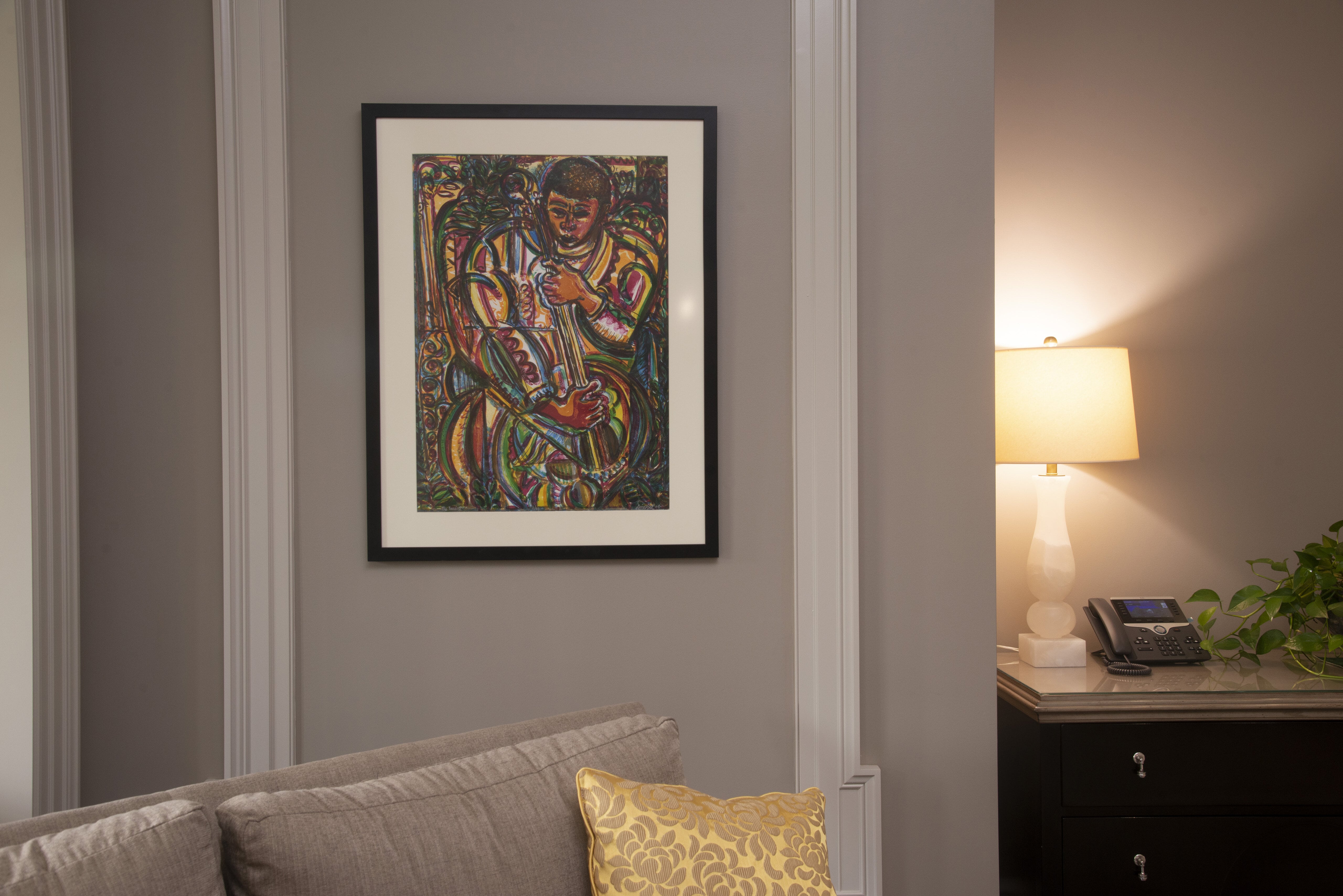 David C. Driskell's print The Bassist is hanging on a wall over a chair.