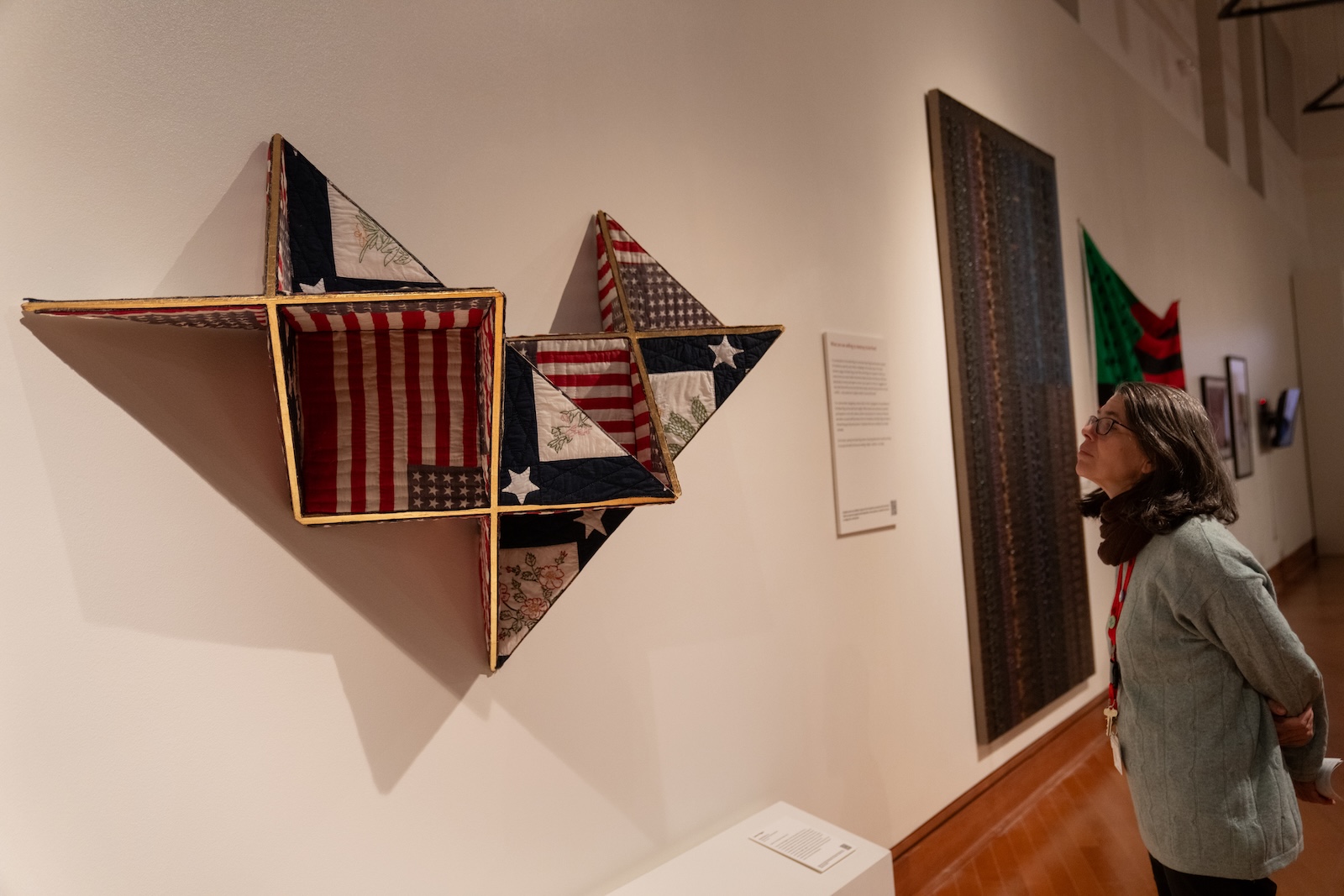 A woman looks at a work of art. She stands to the right and gazes to the left.